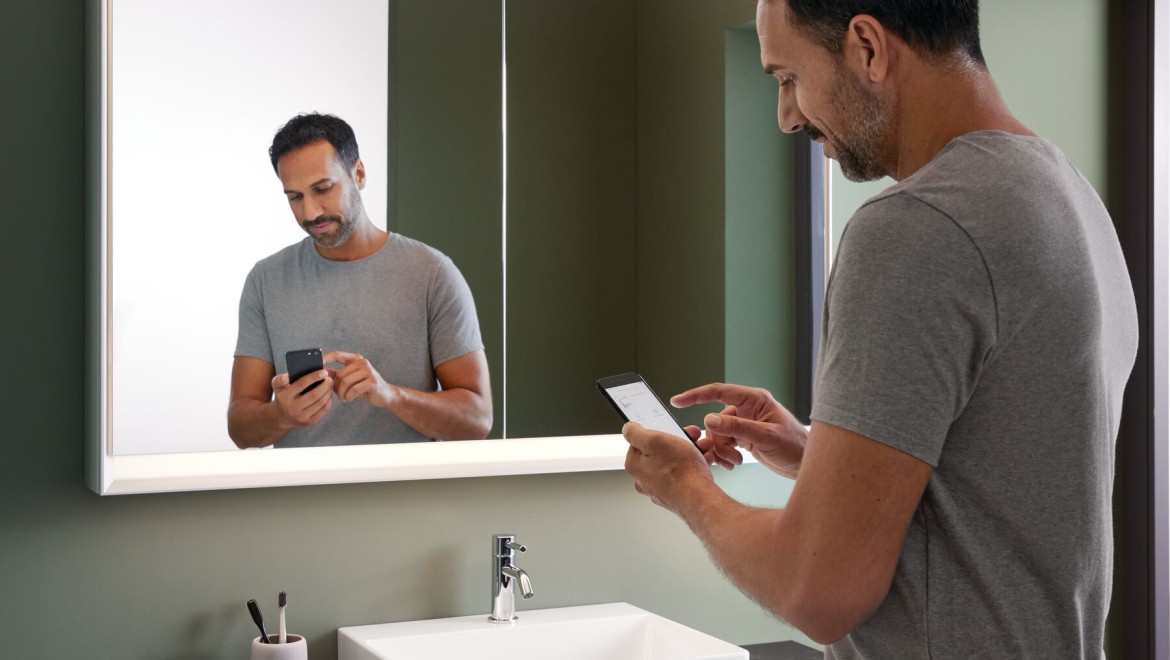 Muž stojaci v kúpeľni s mobilným telefónom