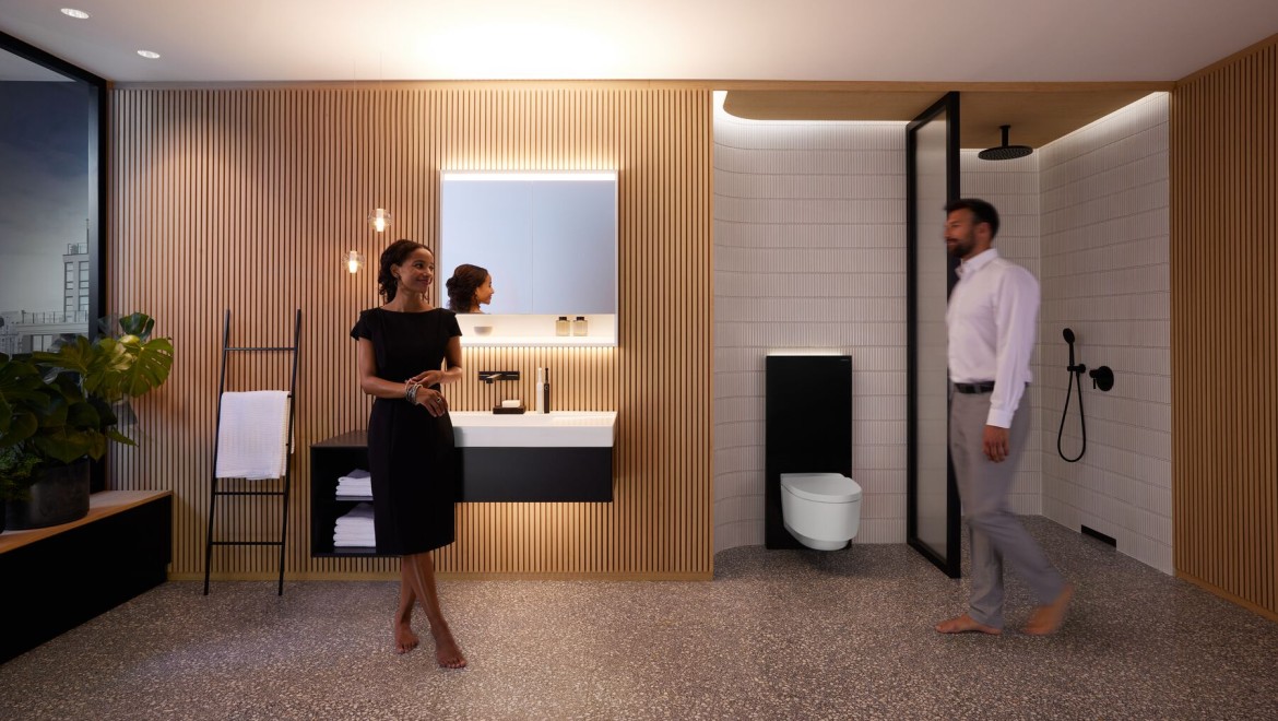 Muž a žena v dokonale osvetlenej kúpeľni s výrobkami Geberit ONE