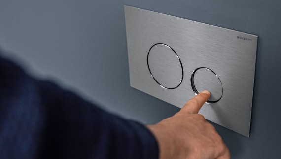 Ruka spúšťa malé splachovanie na ovládacom tlačidle Sigma40 Round (© Geberit)