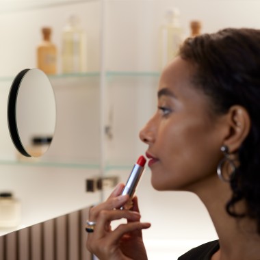Žena nanášajúca si make-up pri pohľade do zrkadla