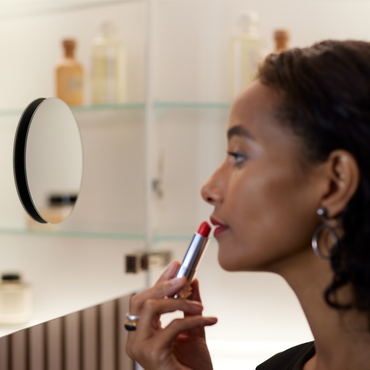 Žena nanášajúca si make-up pri pohľade do zrkadla