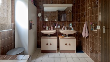 Kúpeľňa s hnedou dlažbou a dvoma umývadlami