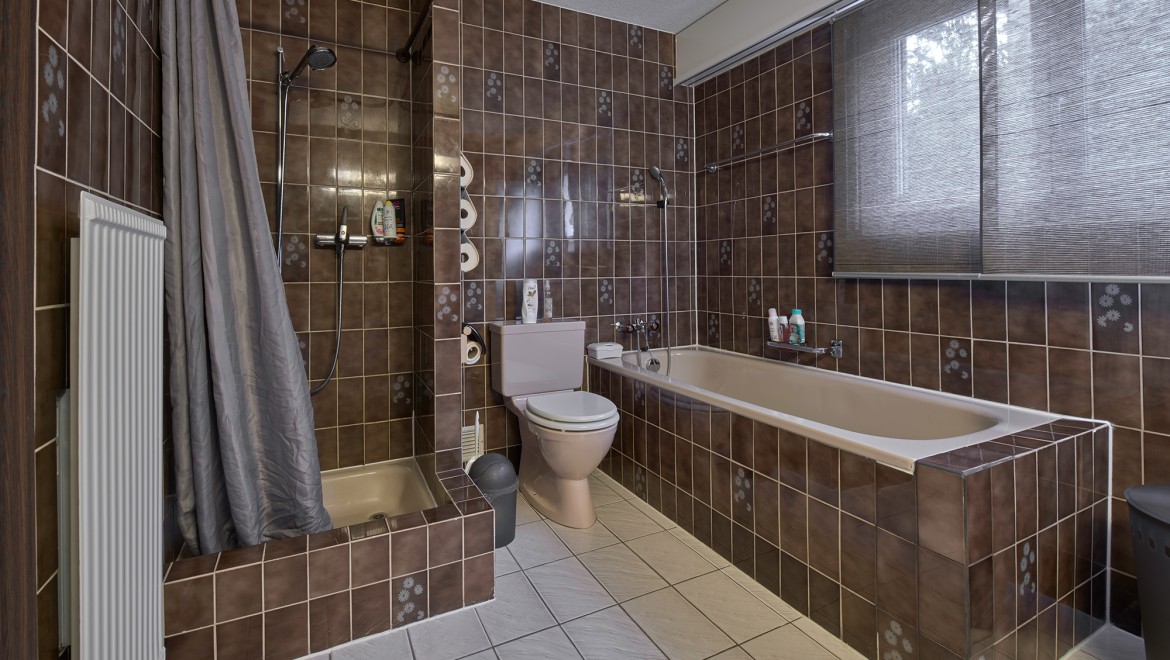 Kúpeľňa s úzkym sprchovým kútom, vaňou a stojacim WC