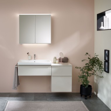 Umývací priestor s kúpeľňovým nábytkom, umývadlom a zrkadlovou skrinkou od spoločnosti Geberit pred pastelovou stenou