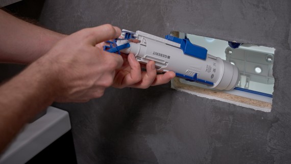 Muž inštaluje splachovací ventil Geberit do podomietkovej nádržky (© Ben Huggler)