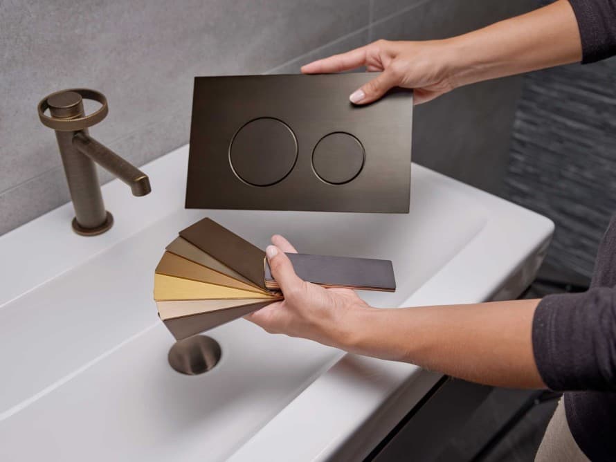 Geberit Sigma40 v odtieni starého bronzu, ladiaca s umývadlovou batériou.