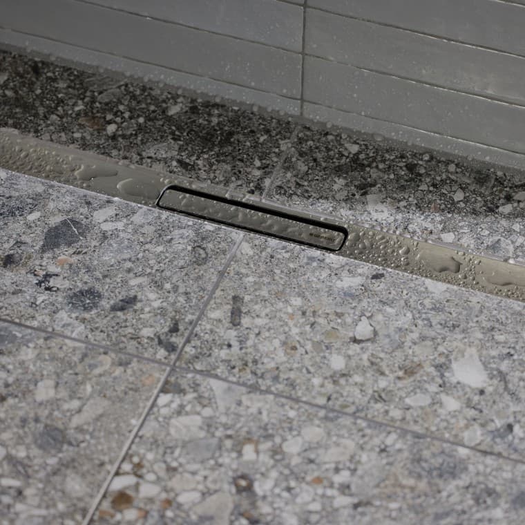 Voda odteká cez elegantný profil z ušľachtilej ocele. Voda odteká cez elegantný profil z ušľachtilej ocele.